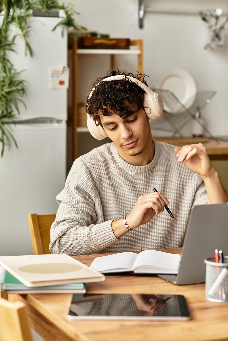 A young person studying with headphones and a laptop