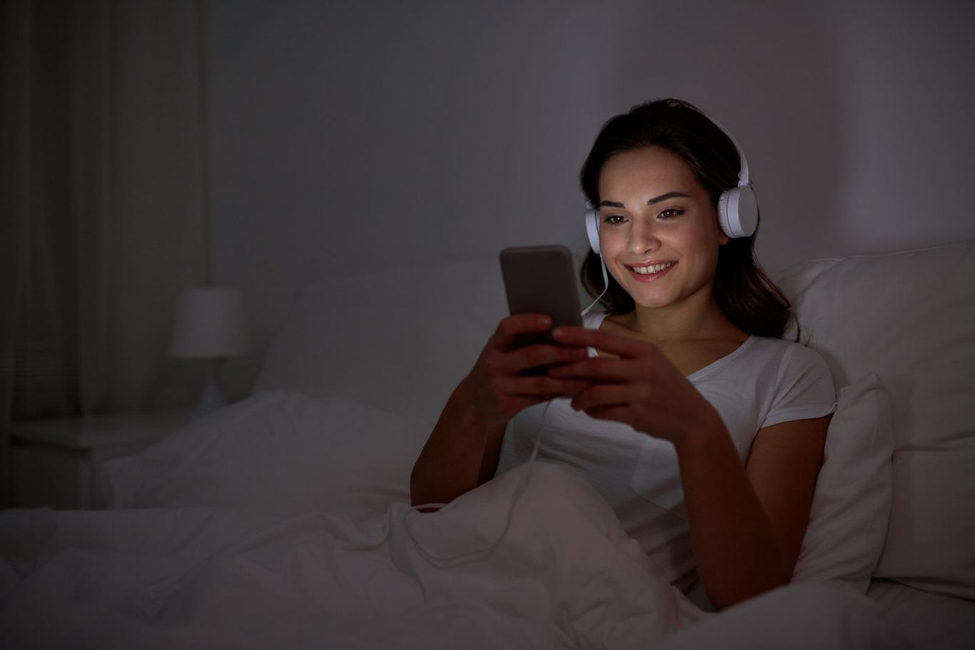 A person listening to music in bed at night