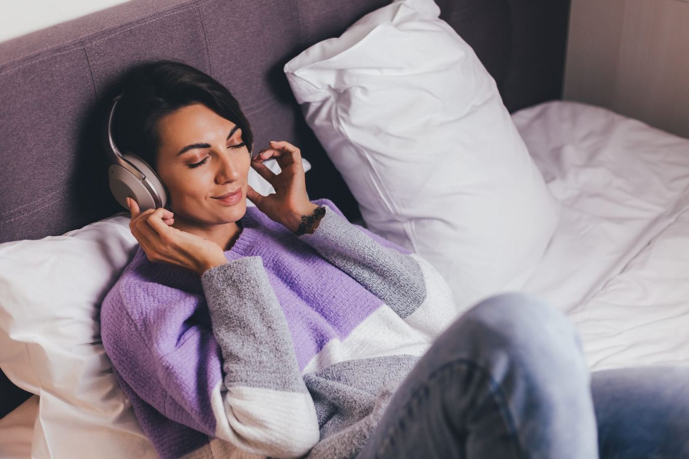 A person relaxing with headphones, eyes closed