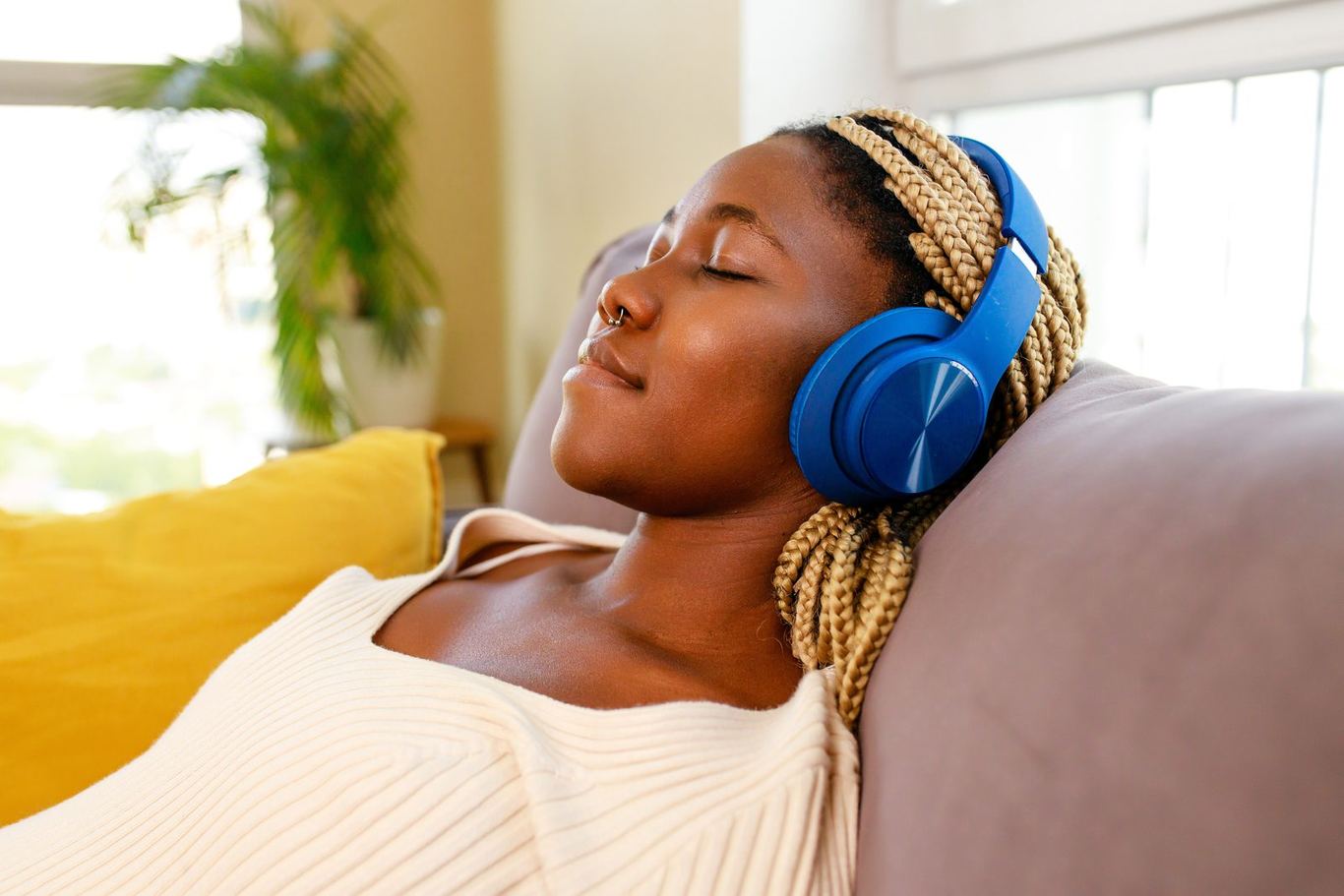 A person relaxing on a sofa with headphones, eyes closed