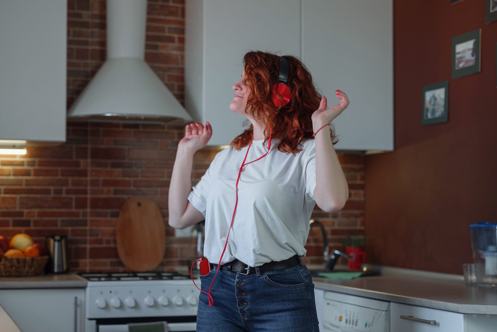 Woman wearing headphones dancing in her kitchen